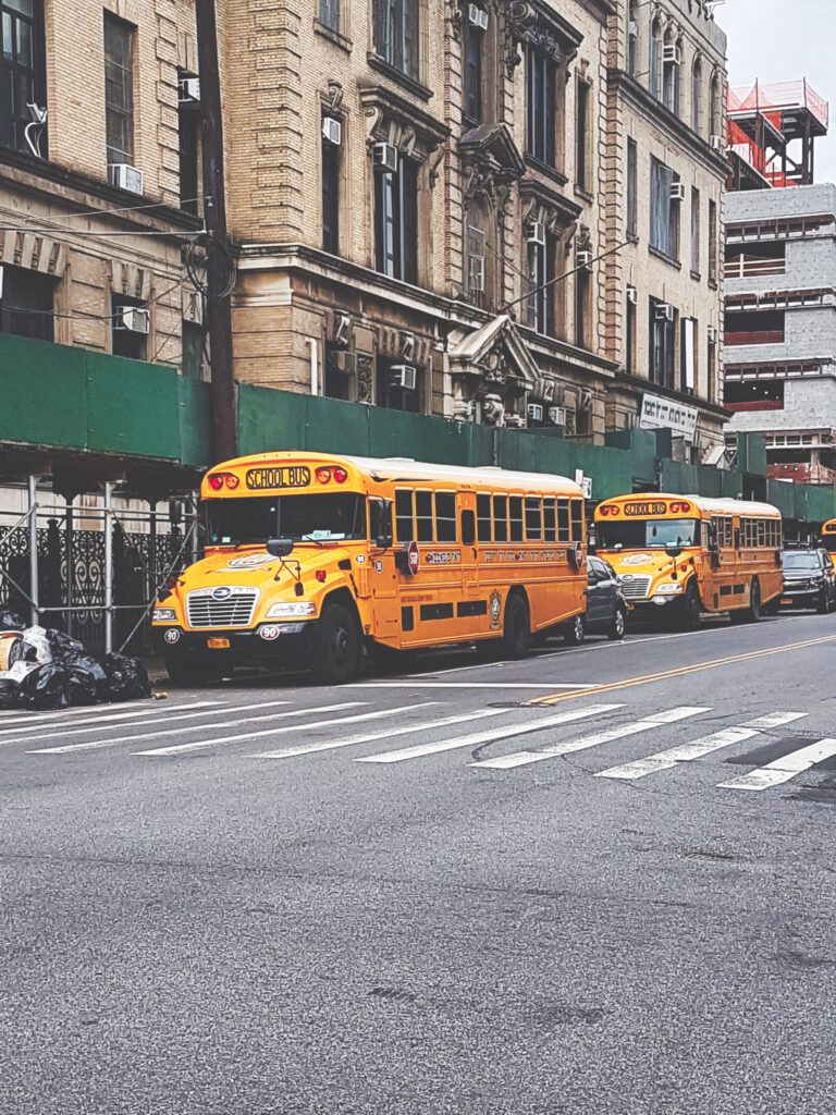 Bild im Hochformat von zwei gelben Schulbussen die vor einem Gebäude in Brooklyn stehen. Aus dem Artikel New York Reise 2019