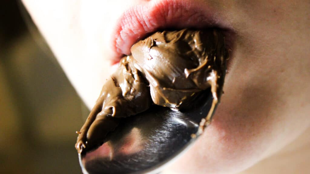 Nahaufnahme von Frau die sich einen Löffel Nutella an den Mund hält. Aus dem Artikel: Akzeptanz und Nutella Tage.