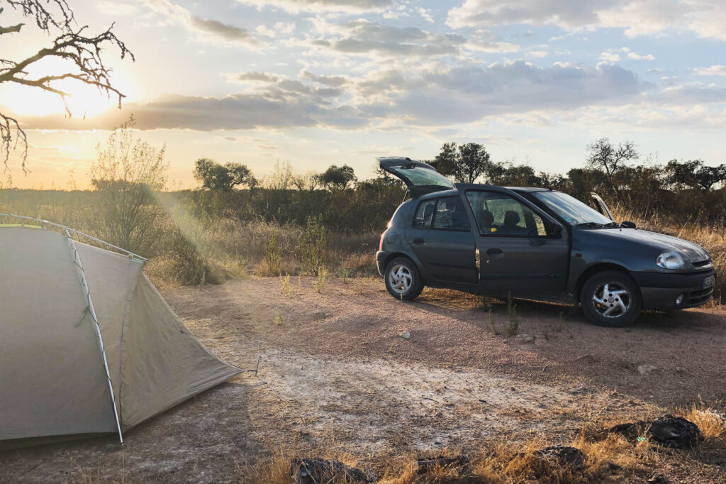 grauer Renault Clio und Zelt in schöner Landschaft mit Sonnenuntergang