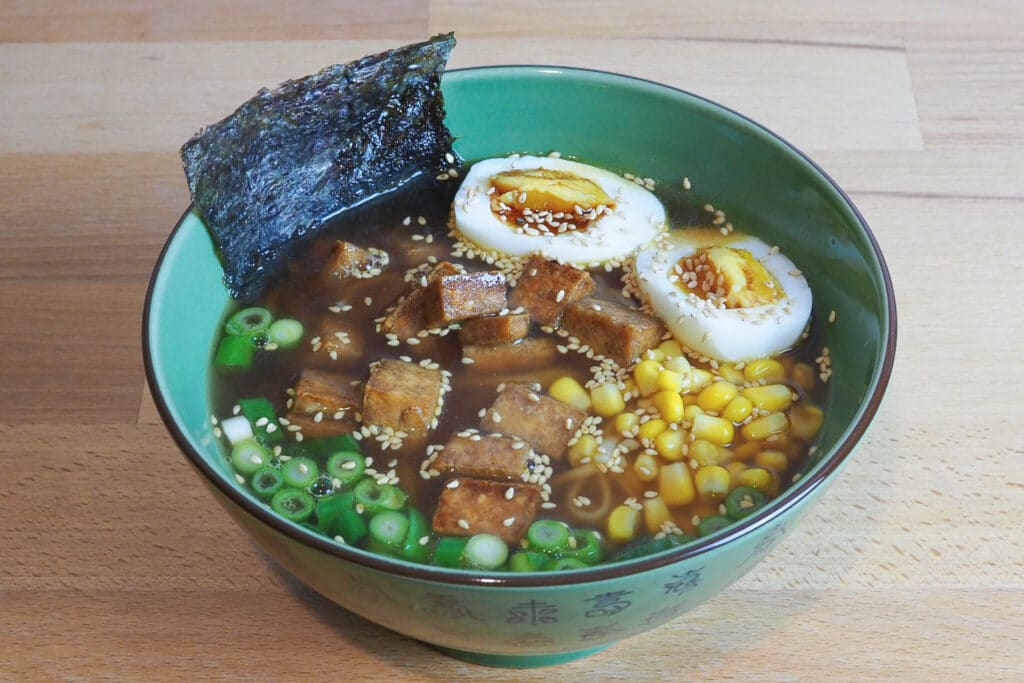 Schüssel mit Shoyu Ramen: Nudeln, Tofu, Mais, Frühlingszwiebel, Nori, Ei, Brühe. Aus dem Artikel Shoyu Ramen mit Teriyaki Tofu – schnell und lecker