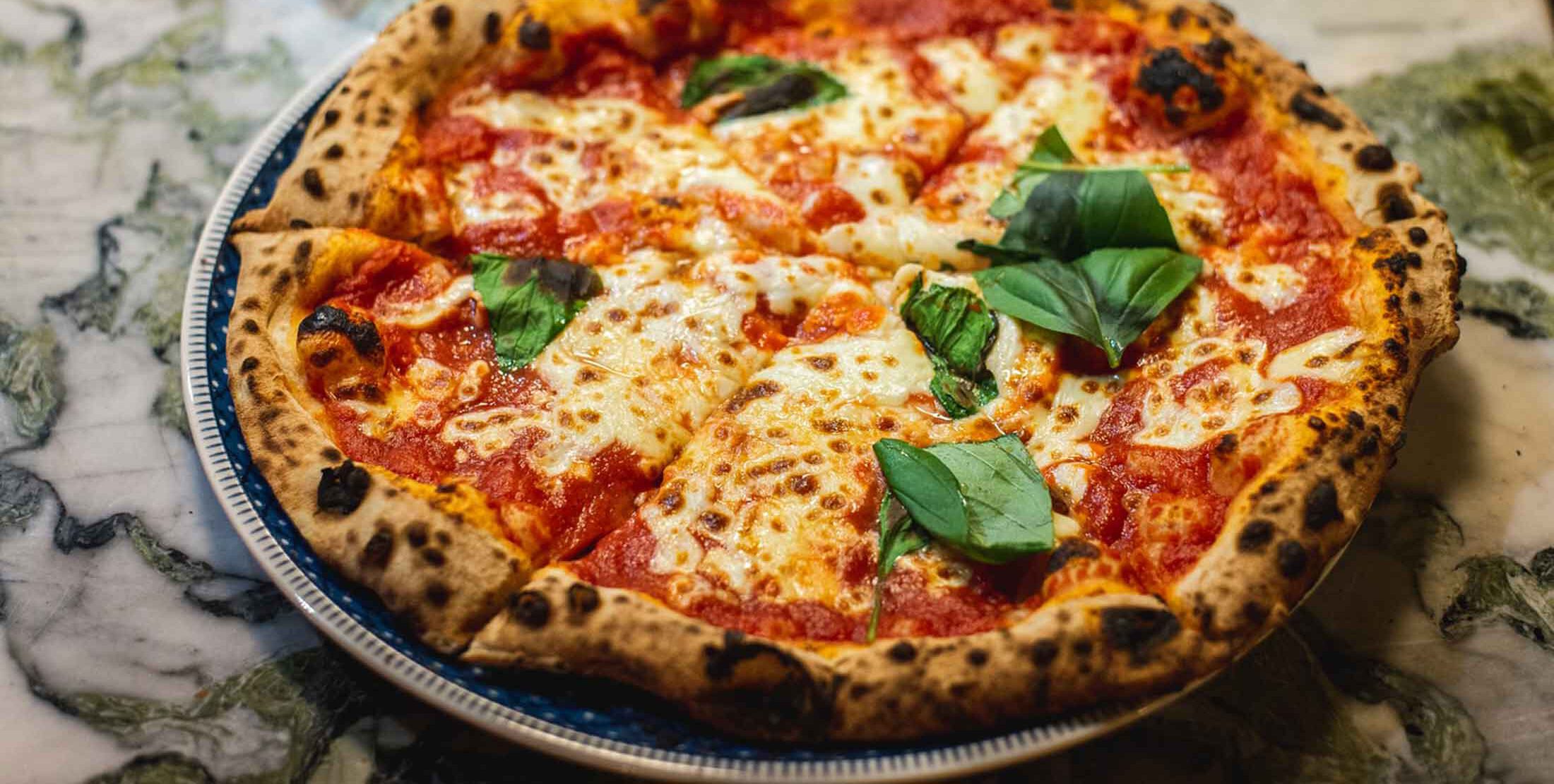 Bild von einer Pizza Margherita mit auf einem Marmortisch. Aus dem Artikel: Top 5 Pizza in Friedirchshain