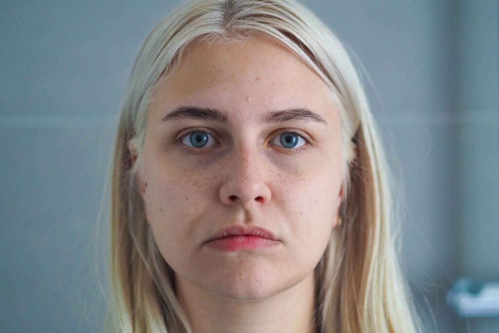 Portrait einer jungen blonden Frau die emotionslos in die Kamera schaut. Aus dem Artikel: Etwas ist jetzt anders. Panikattacke