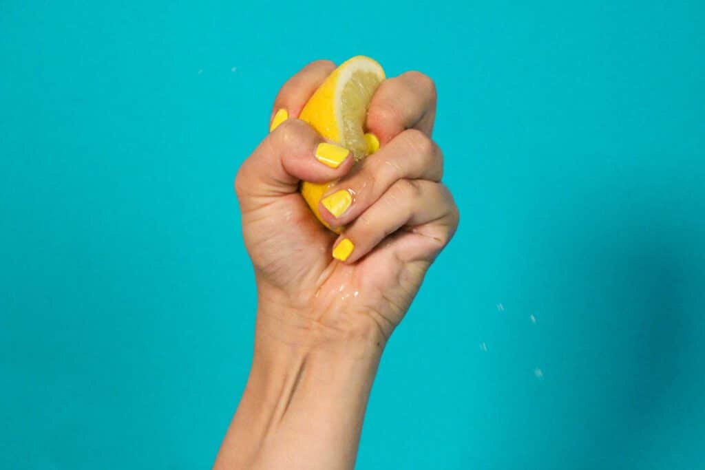 Eine weibliche Hand mit gelb lackierten Fingernägeln, die eine halbe Zitrone zerdrückt.Aus dem Artikel: ADHS Awareness Month – für dich ein Monat, für mich 12